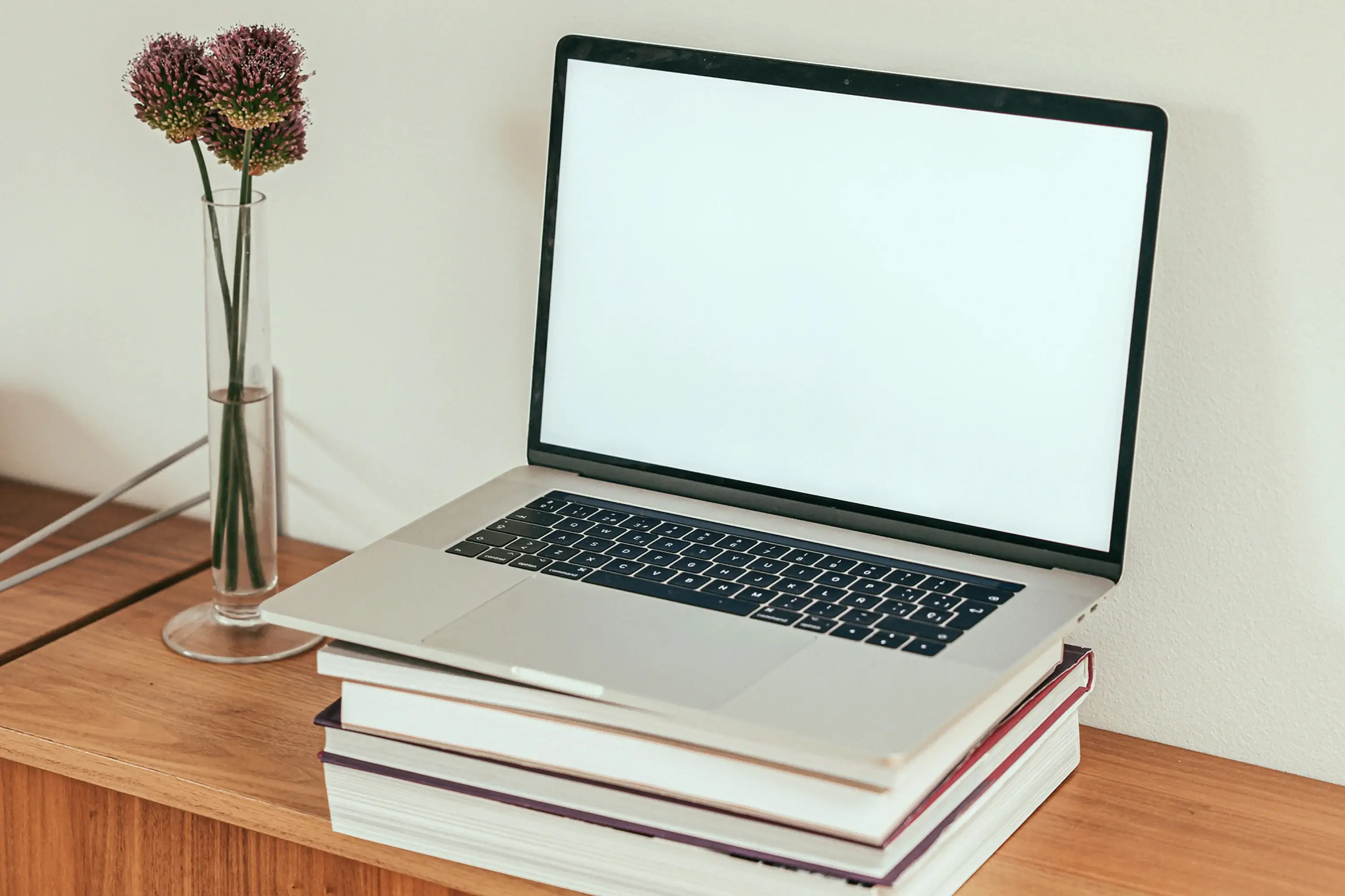 an open laptop with a blank screen balancing on a stack of books